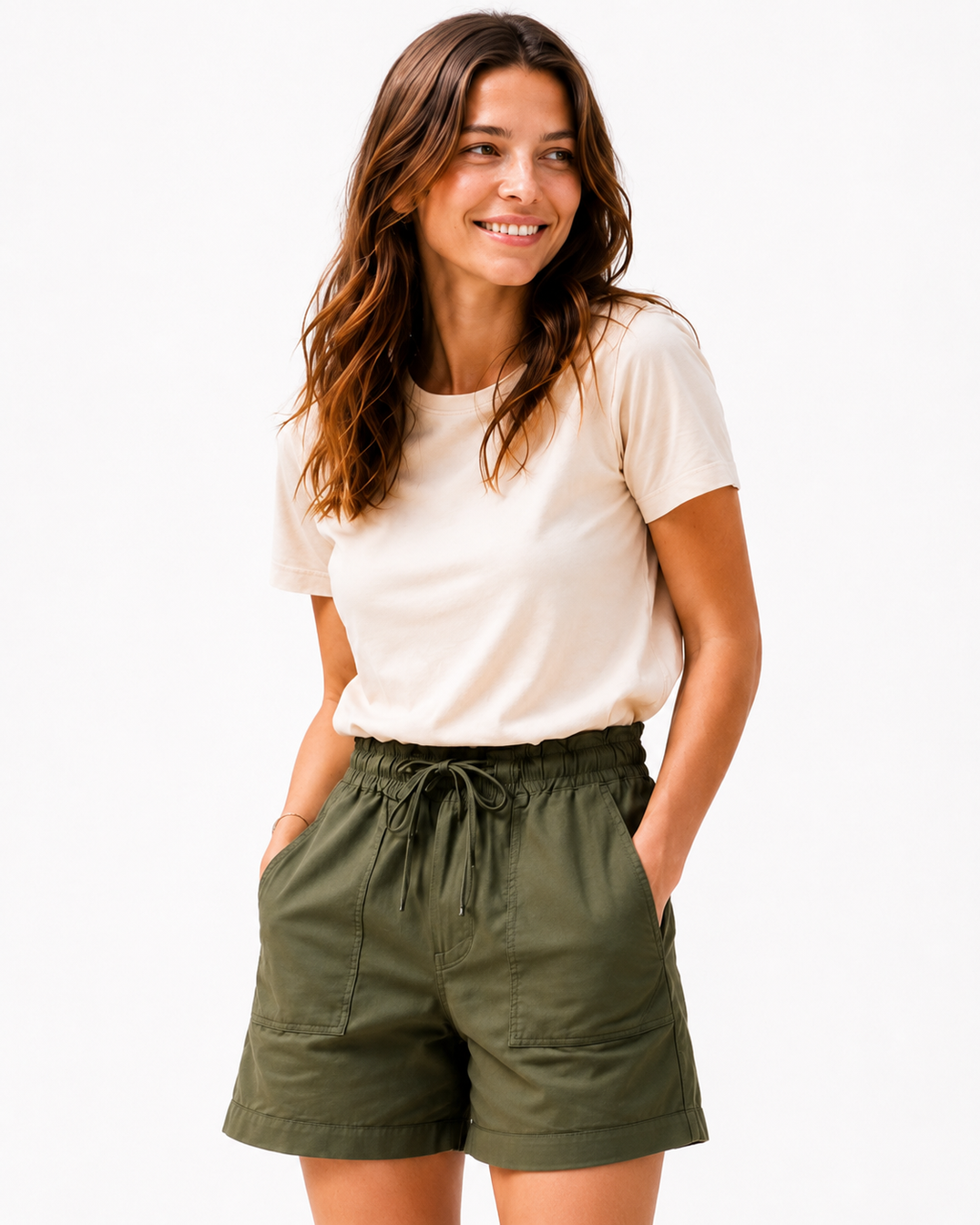 A woman modeling olive green drawstring shorts and a cream t-shirt against a plain white background.